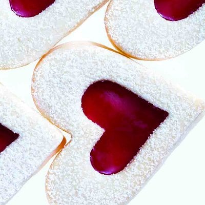 A stack of Raspberry sugar-cookie heart cookies on a white background.