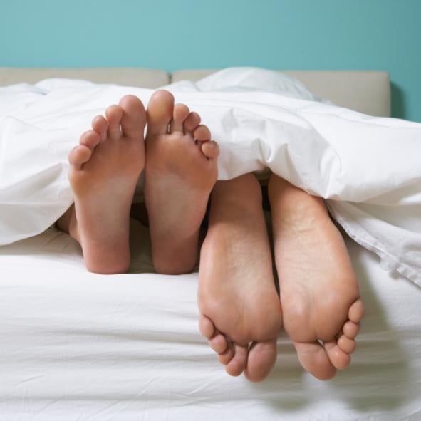 A couple in bed with their feet showing