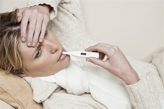 sick woman taking her temperature, thermometer