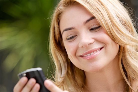 A blond woman looking at her cell phone