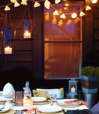 outdoor dining with hanging lights and candles in evening