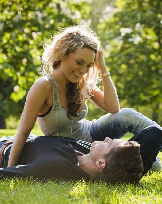 couple on grass, romance, blonde girl smiling at boyfriend