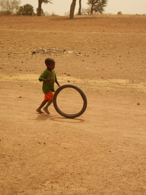 little boy playing with tire, Mali, West Africa
