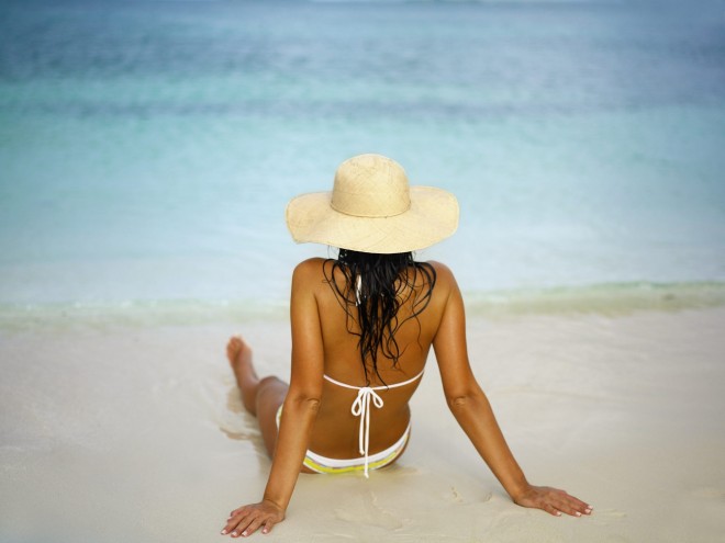 Woman lying on the beach with a sun hat on