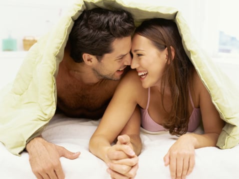 young couple, man and woman, lying bed playful and smiling, romantic love