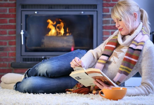 blonde woman reading book by fireplace