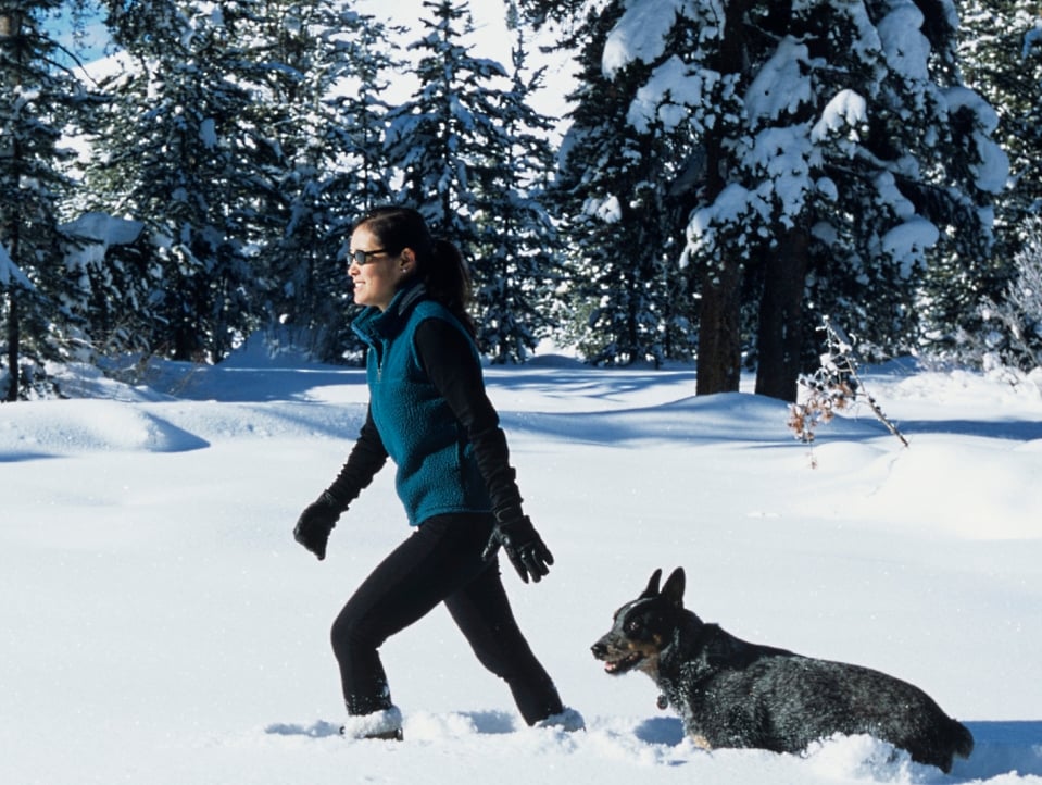 Woman walking in the snow with her dog