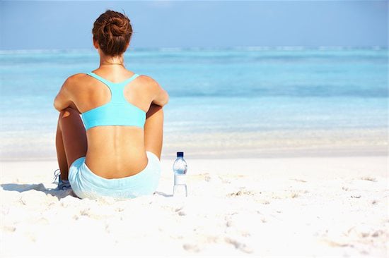 Rear view of woman enjoying the view of horizon on beach after workout