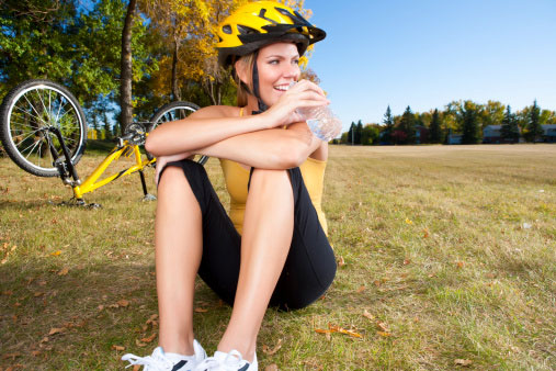 Smiling female biker drinking water