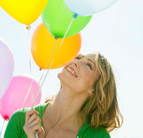 A happy woman holds a bunch of balloons