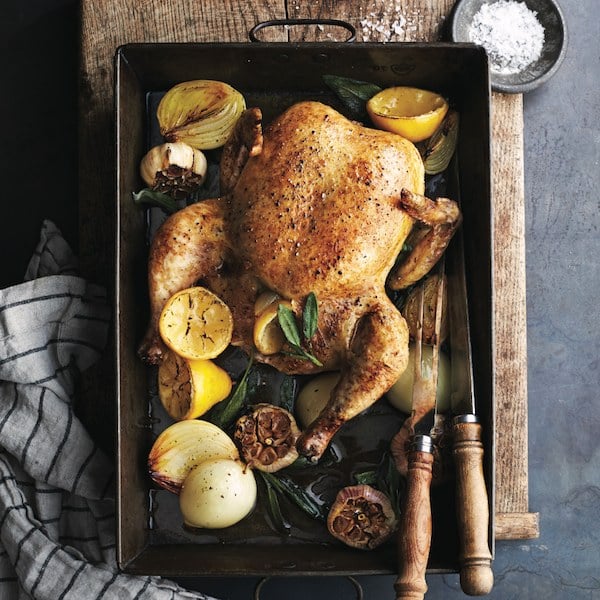 Classic roasted chicken with lemon, sage and garlic on roasting pan