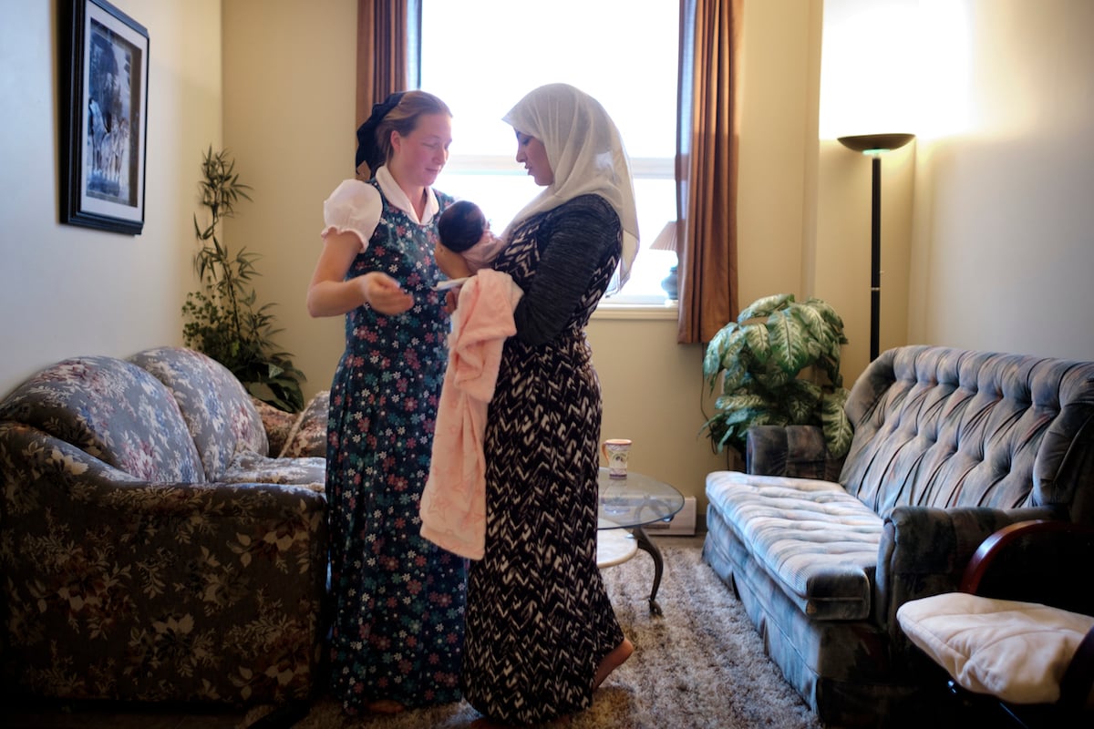 Elaine Hofer helps Najwa Hussein take care of her newborn daughter Janna in Brandon, Man.