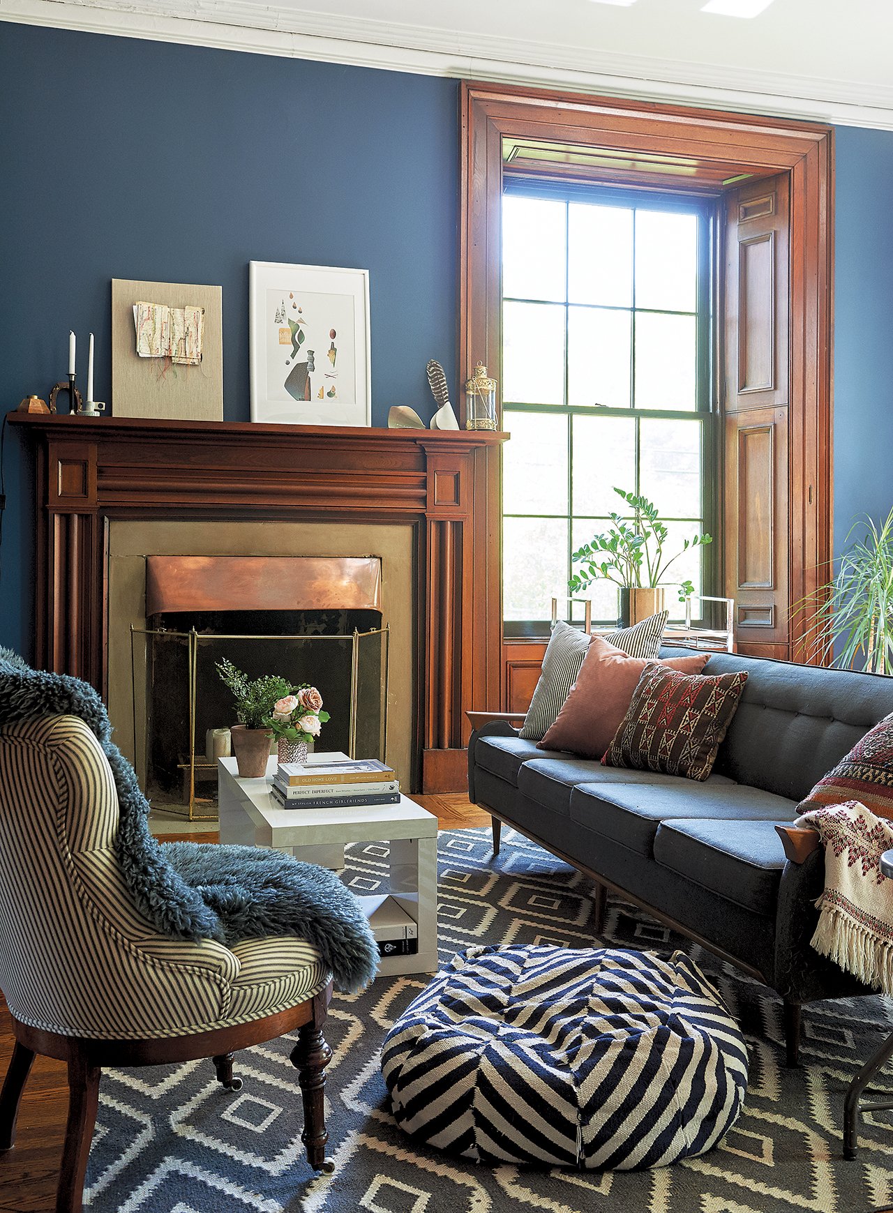 The sitting room of the stone house is warm and comfortable yet modern and chic, with cool paint tones, warm wood, comfy chairs, and throw cushions and pillows.