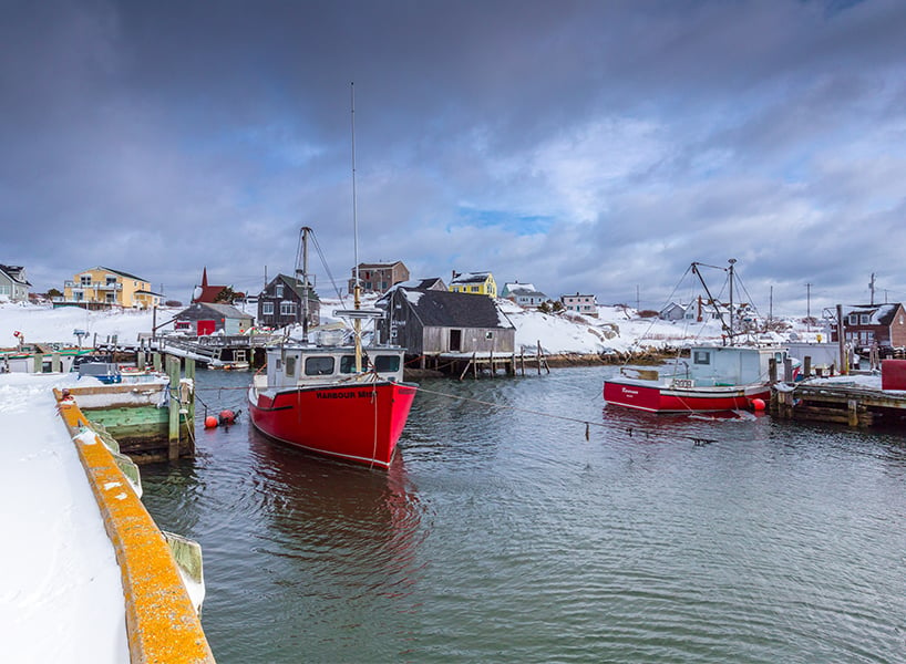 best outdoor winter activities-Peggy's Cove Bay with brightly coloured boats and a dark winter sky