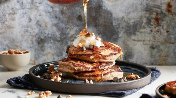 a stack of banana bread pancakes with syrup being drizzled overtop