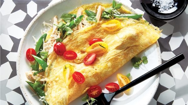 chicken omelettes filled with snap peas and basil, topped with tomatoes, served on a white plate