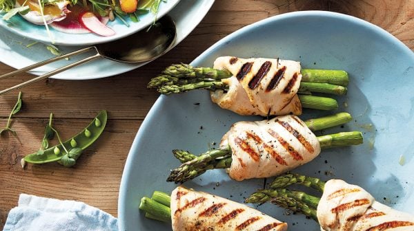 Grilled asparagus-stuffed chicken on a blue plate.