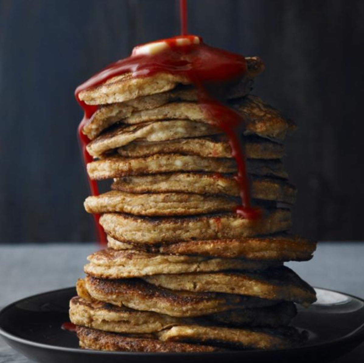 Stack of pancakes topped with red syrup