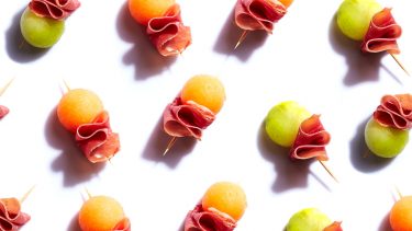 melon and prosciutto skewers on a white background