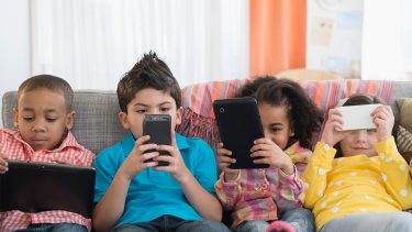 children using technology on sofa