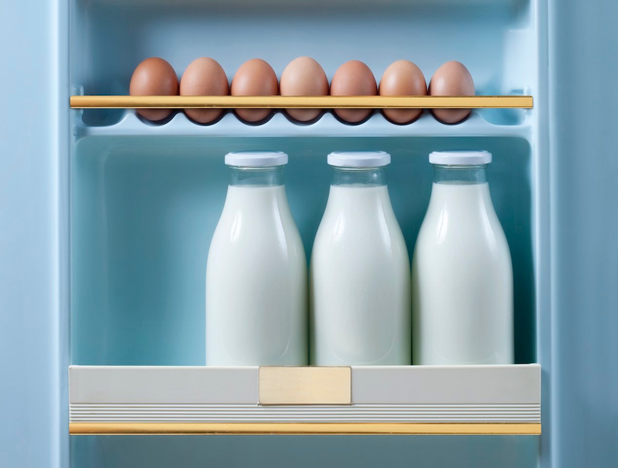 Expiry dates: 3 bottles of milk and brown eggs in retro fridge door