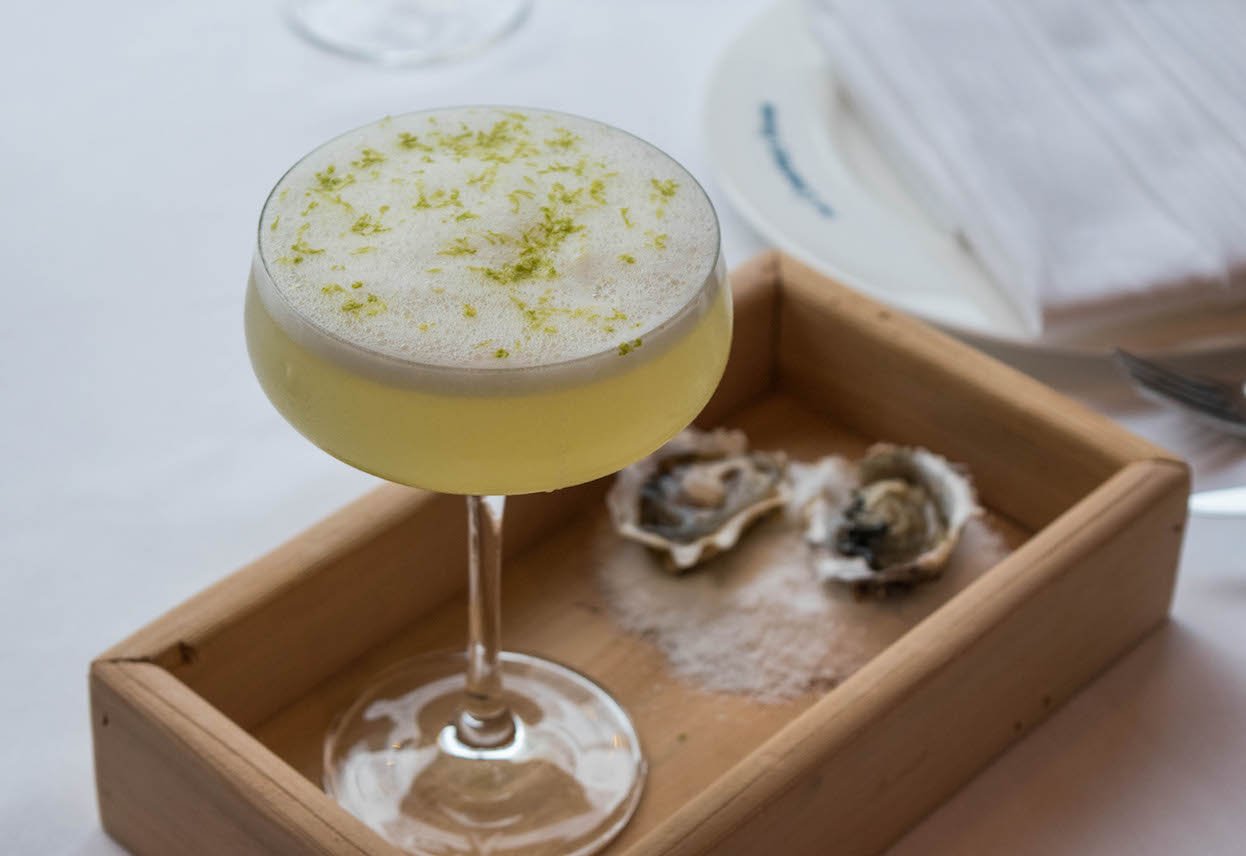 Cocktail coupe in wooden box with two oysters.