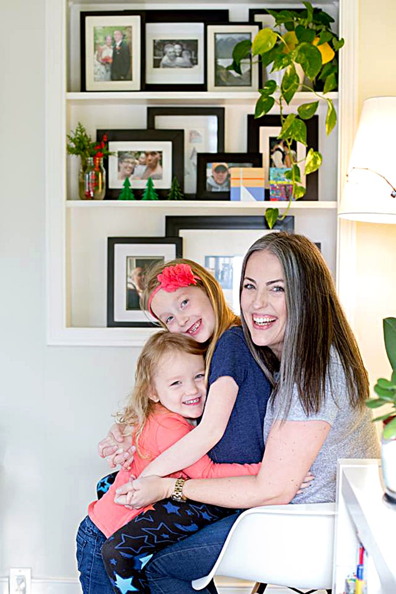 opioid addiction stigma-a woman poses with her two daughters in their living room