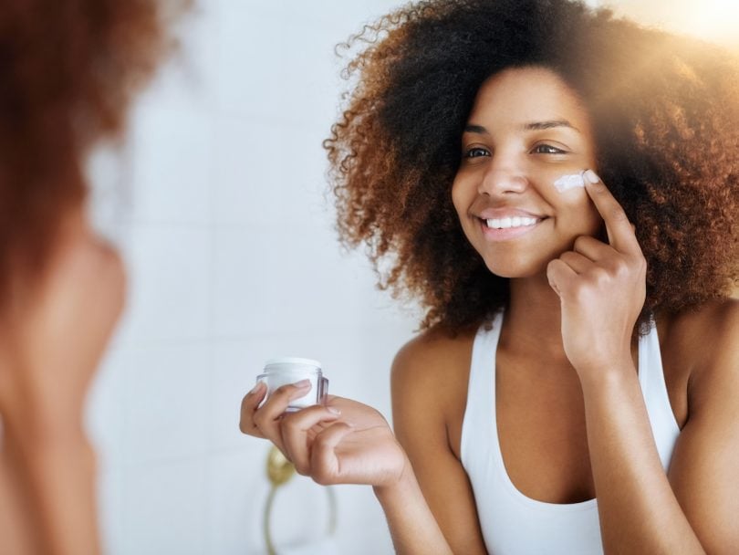A woman applies moisturizer. How many skincare products do you really need? Do you actually need a serum?