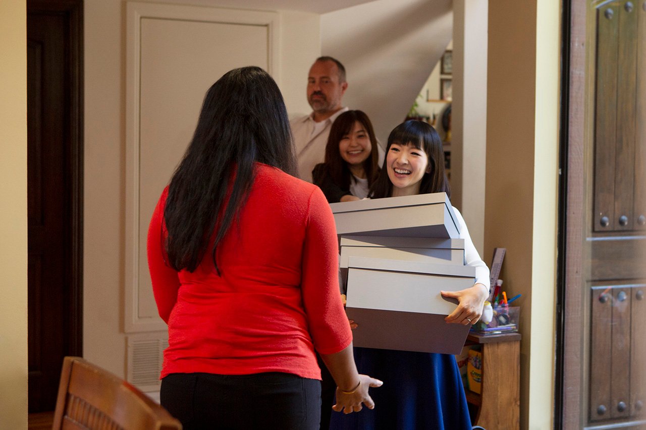 tidying up with marie kondo show: man, woman, and kondo walks into house with boxes towards woman in red