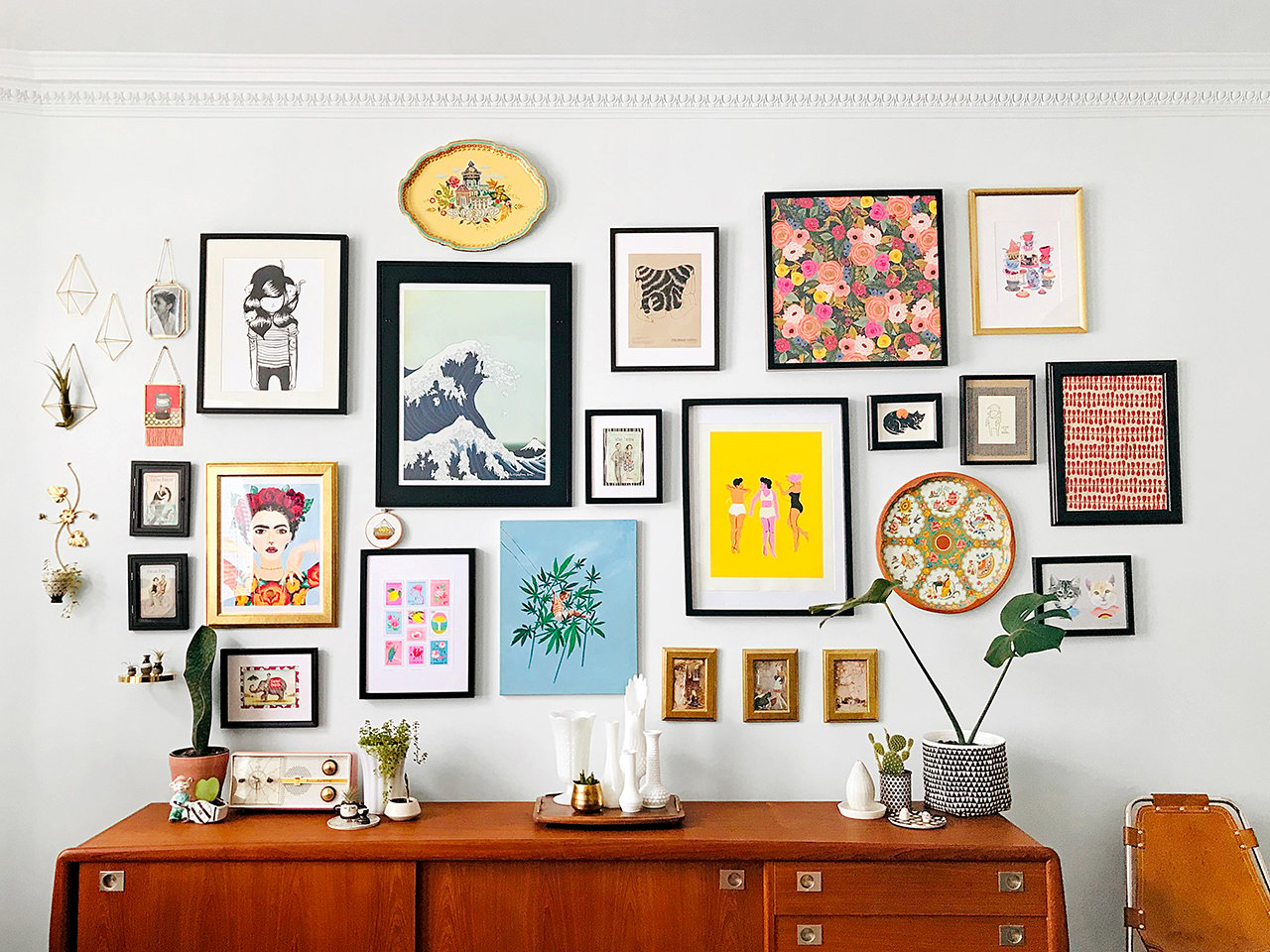 gallery wall- an assortment of art and objects hang on a wall above a sideboard