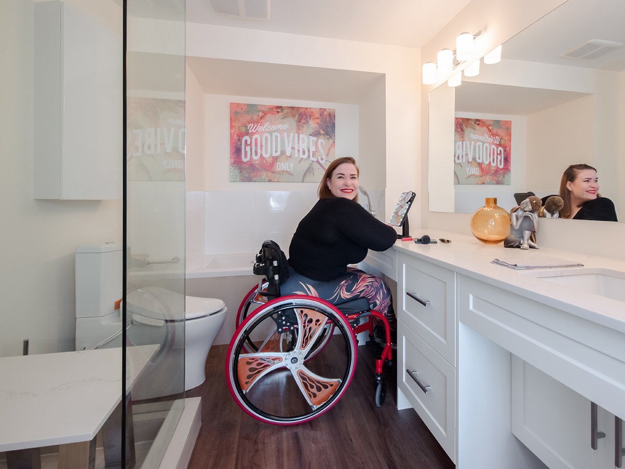 Jenna Reed-Côté's universal design renovations: Woman in wheelchair sits at makeup counter in her washroom