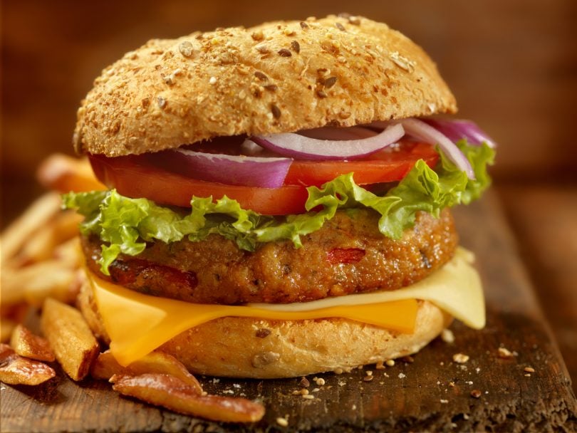 ultra-processed foods-veggie burger on a bun with onion, tomato, lettuce and cheese.
