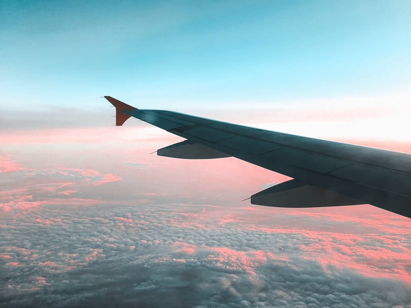 View of airplane wing above sky — how do airplanes affect the environment?