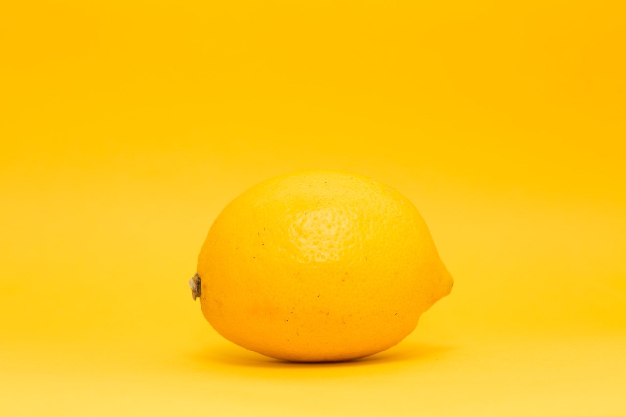 A single lemon on a yellow background