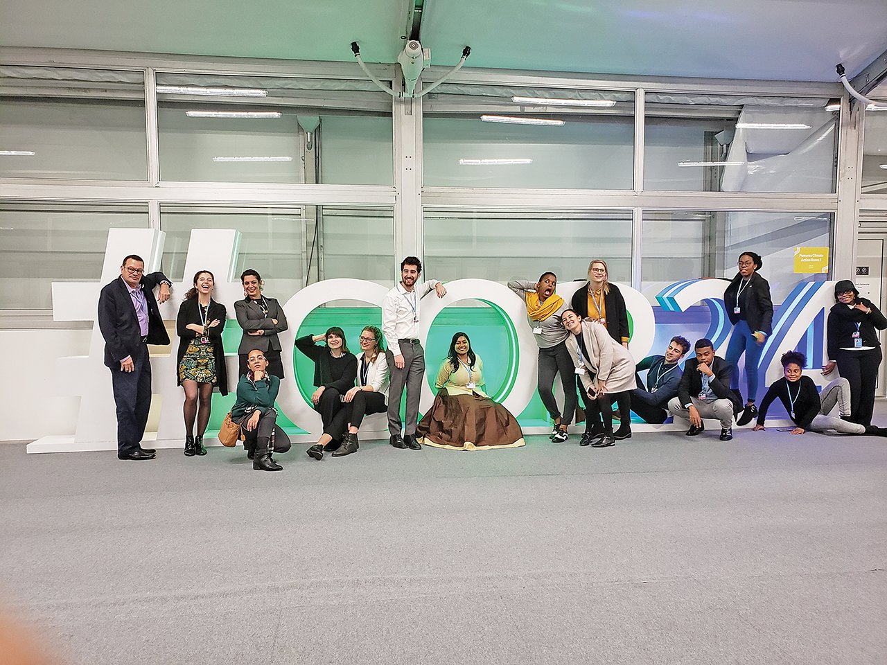 Ana Gonzalez Guerrero and Dominique Souris stand with Youth Climate Lab members in front of #COP24 sign