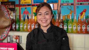 Chef Elia Herrera of Colibri standing behind the register in her restaurant