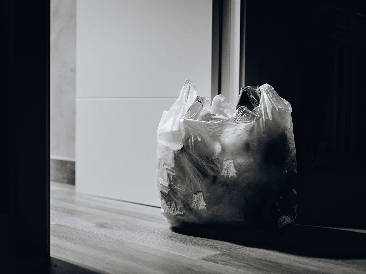 reuse single-use plastics: black and white grocery bag of garbage by door