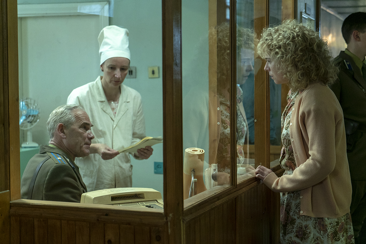 HBO Chernobyl scene: Jessie Buckley as a firefighter's wife approaches two people behind glass