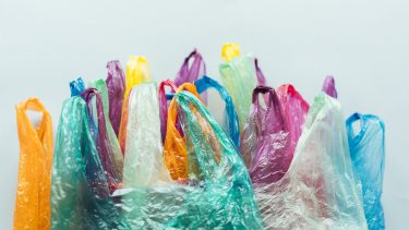 Many multicoloured plastic bags grouped together against a neutral background.