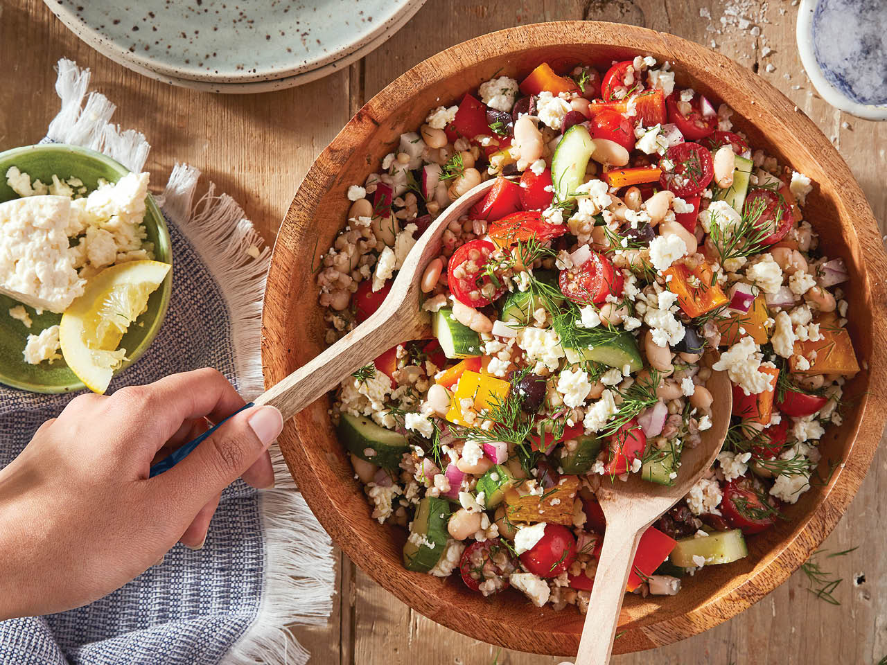 Overhead shot of a wooden bowl filled with Greek Salad with Toasted Buckwheat