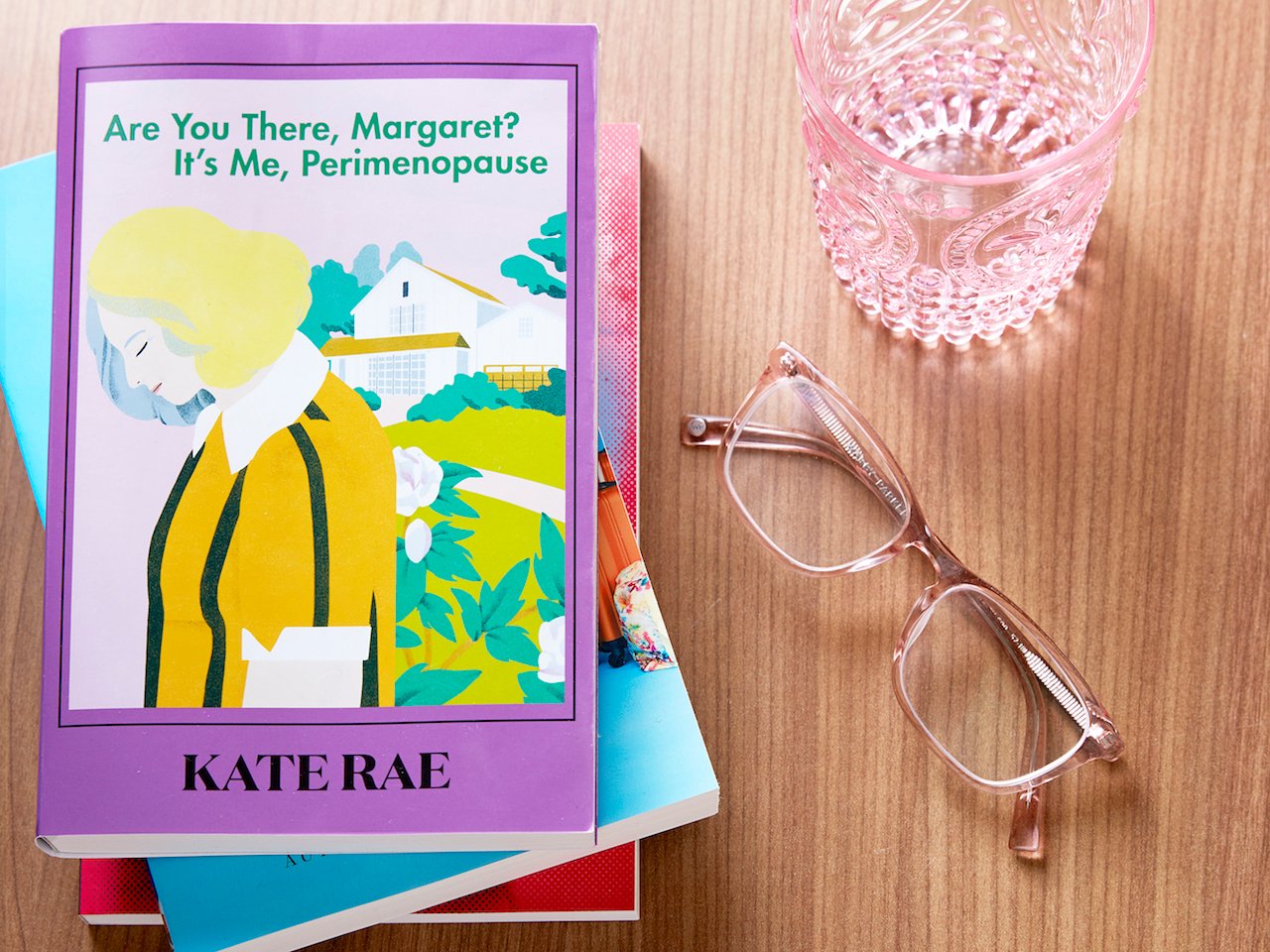 Overhead shot of a stack of books, glasses, and an empty glass of water. Top book on stack says "Are you there, Margaret? It's me, Perimenopause" and shows a blonde woman hanging her head