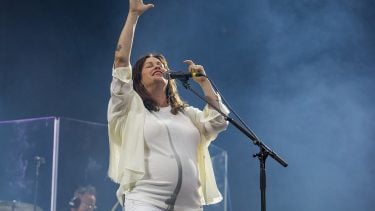 Alanis Morissette Self magazine profile: Alanis in all white performing with one arm raised high and mist rising behind her