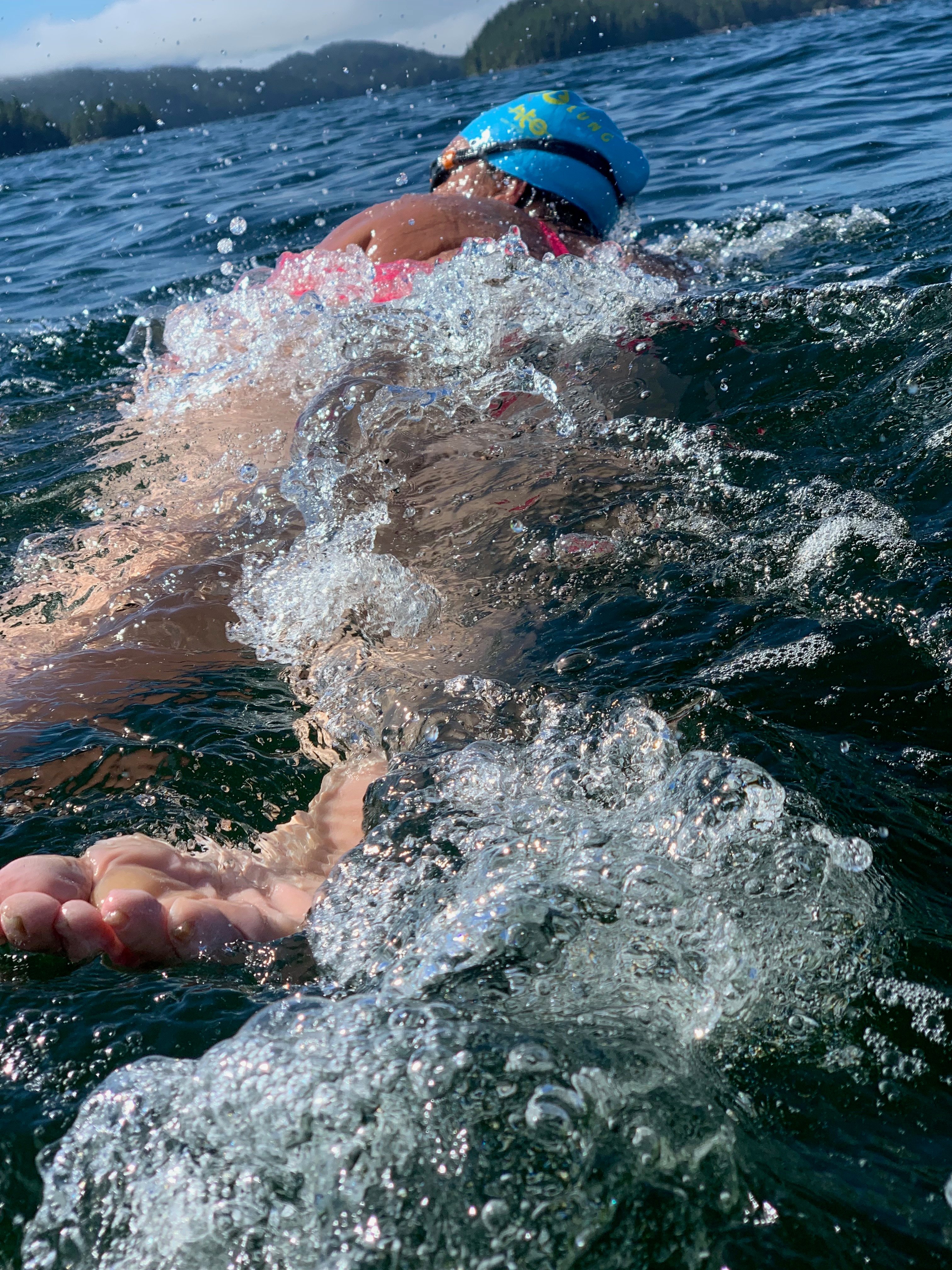 Susan Simmons swimming, close up on her feet hitting the water.