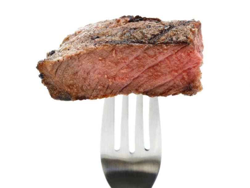 a small piece of steak speared on the end of a silver fork