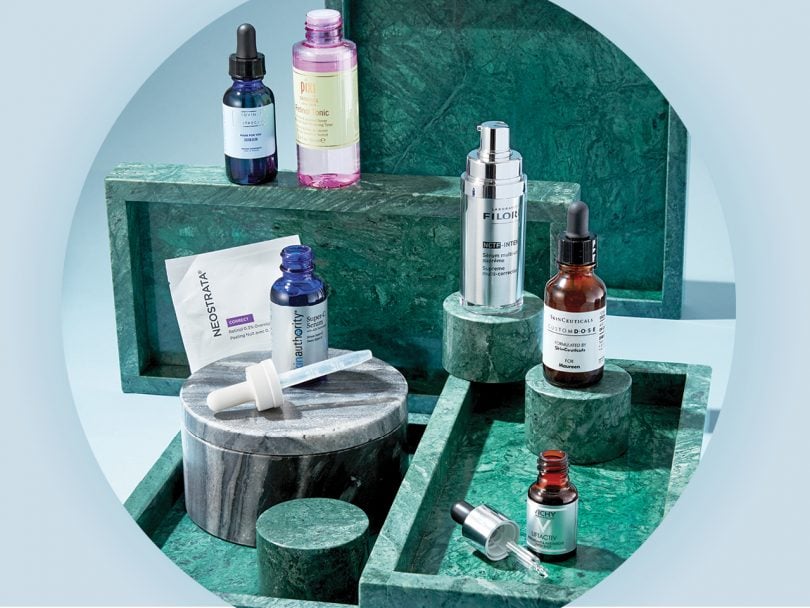 A few bottles of serums sit on green marble trays