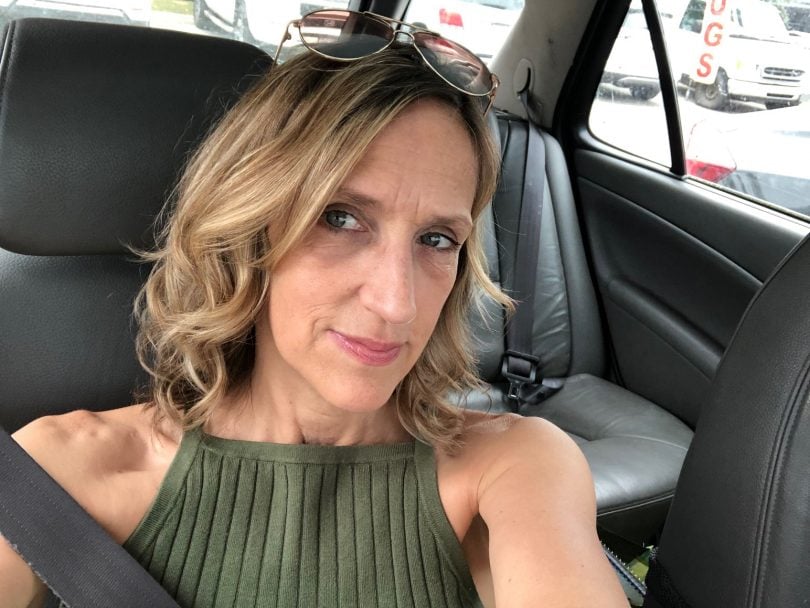 a woman takes a selfie wearing a green shirt in her car