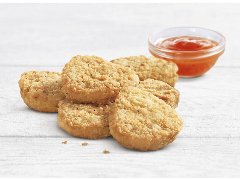 A&W new plant-based nuggets next to a bowl of sauce on a white wooden table.