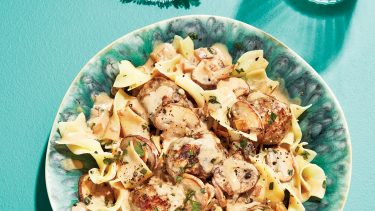 Swedish meatballs and egg noodles in turquoise bowl.