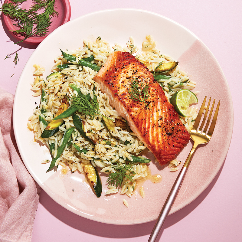 Pink plate topped with orzo and salmon.