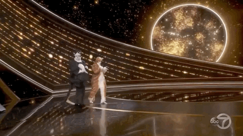 James Cordon and Rebel Wilson in cat suits walk across the Oscars stage